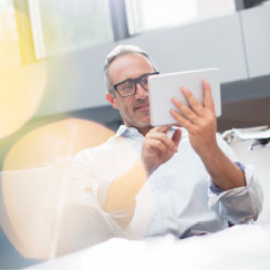 Man in white on couch with light tablet