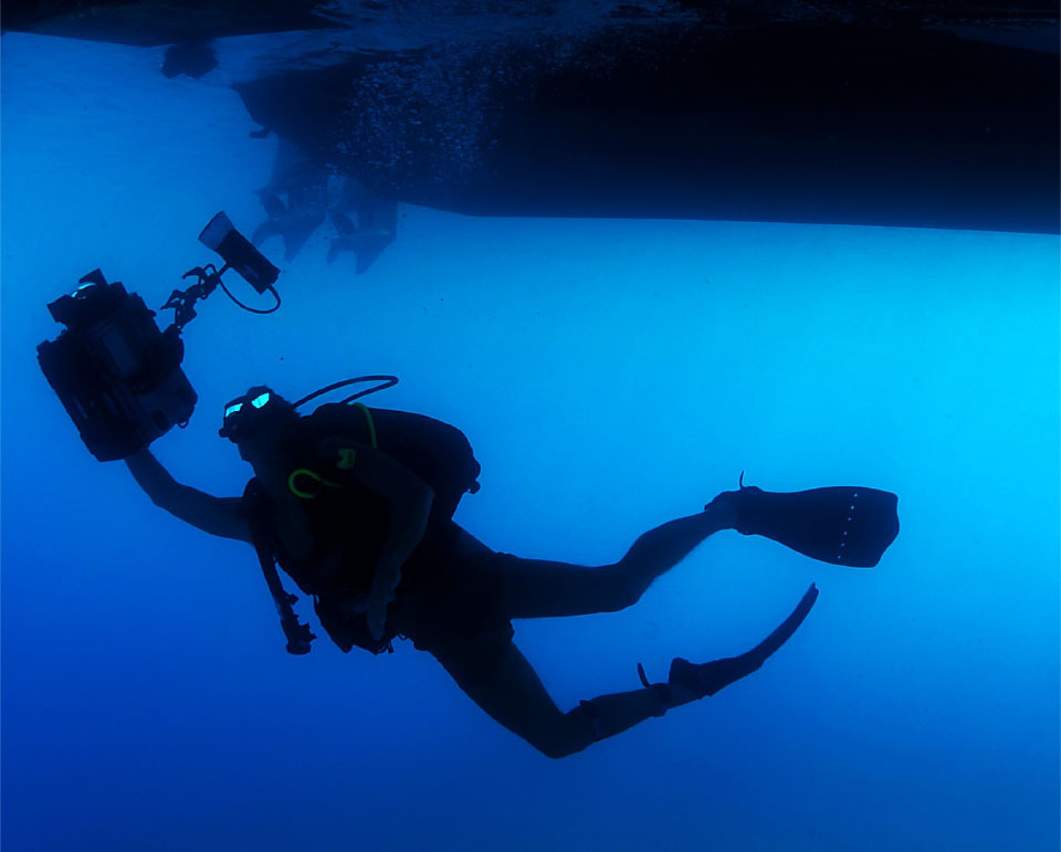 Scuba diver with camera under boat