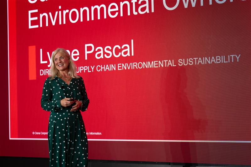Lynne standing on stage in front of a presentation about sustainability 