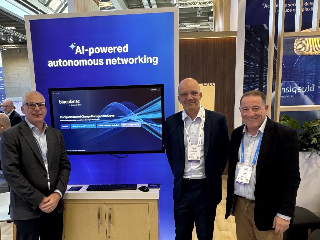 mosaic_DTW1 Three attendees stand beside a Blue Planet exhibit showcasing an AI-powered autonomous networking demonstration at a technology conference.