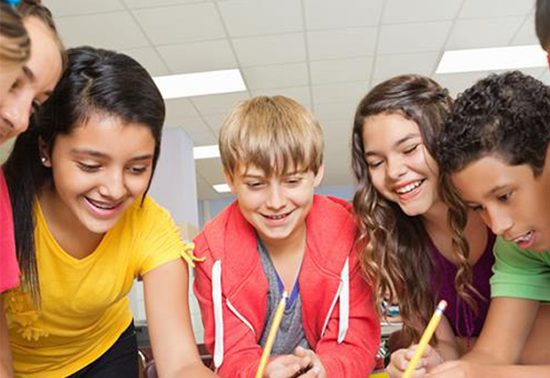 Kids gathered around a desk writing