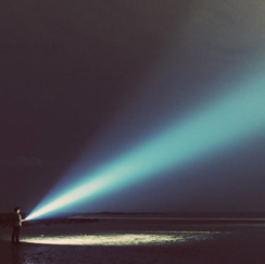 Young boy shining a flashlight into the night sky