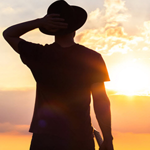 Silhouetted man with hat and sun