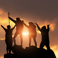 Silhouetted hikers at peak summit