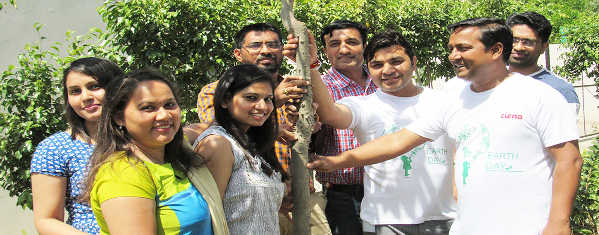 a group of ciena employees standng by a tree
