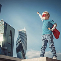 Boy with cape and mask, buildings in background