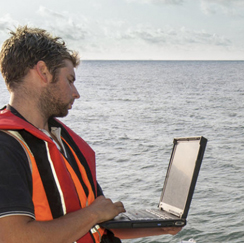 Man on the ocean with a laptop