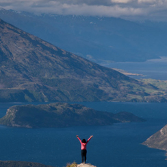 Person arms extended above mountain and water