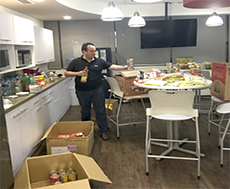 Ciena volunteer standing in breakroom with cartons of food