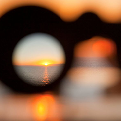 Binoculars looking toward an ocean sunset
