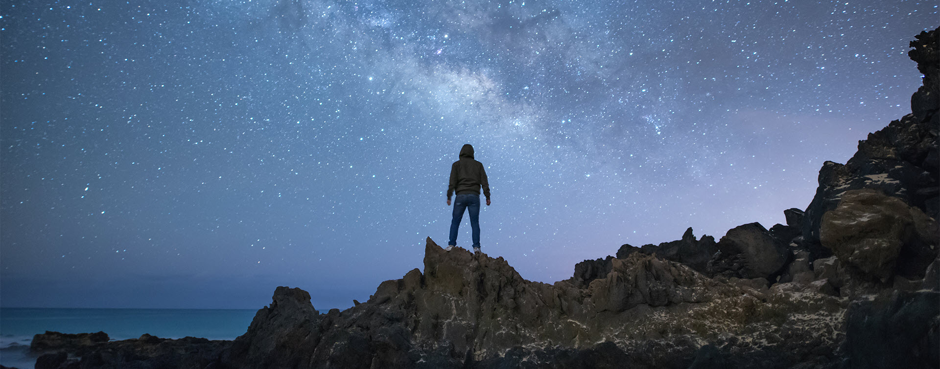 Person climbing cliffs looking over ocean