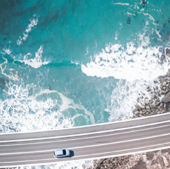 Car driving on road next to ocean shoreline