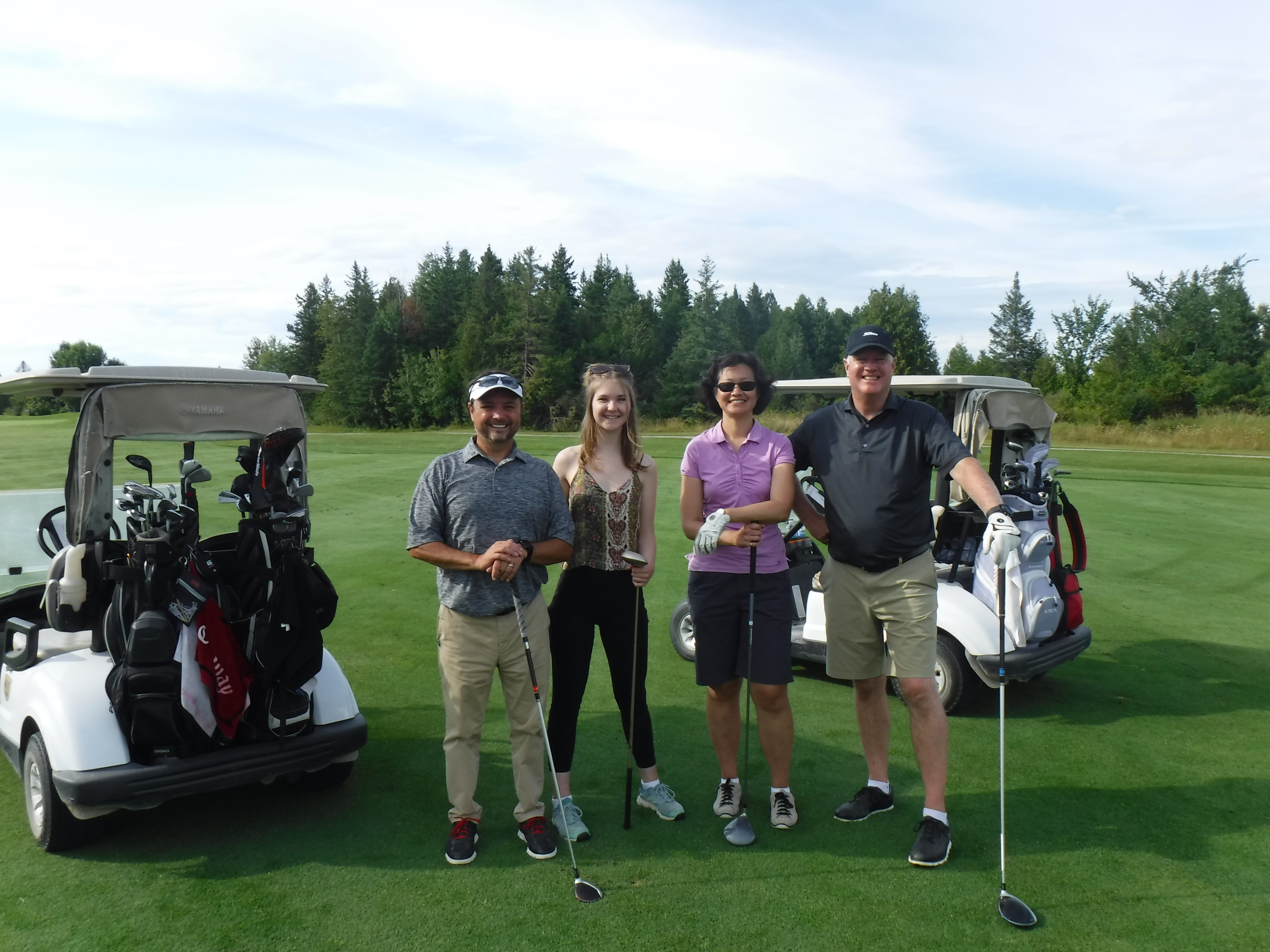 Two men and two women smiling together on golf course