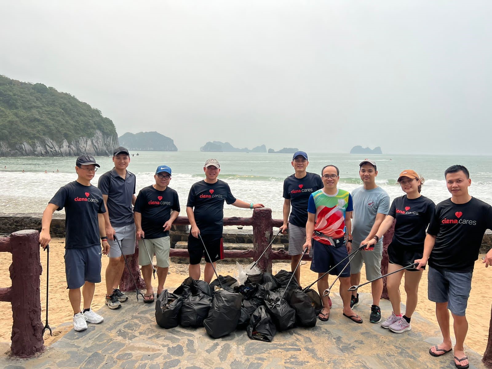 Men and women on a beach with full trash bags 