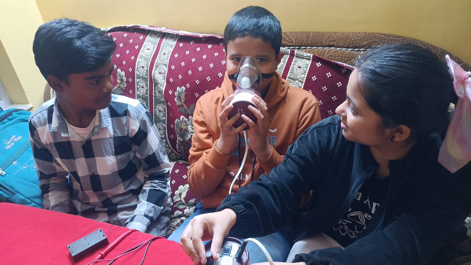 A student tests an oxygen device while two others help