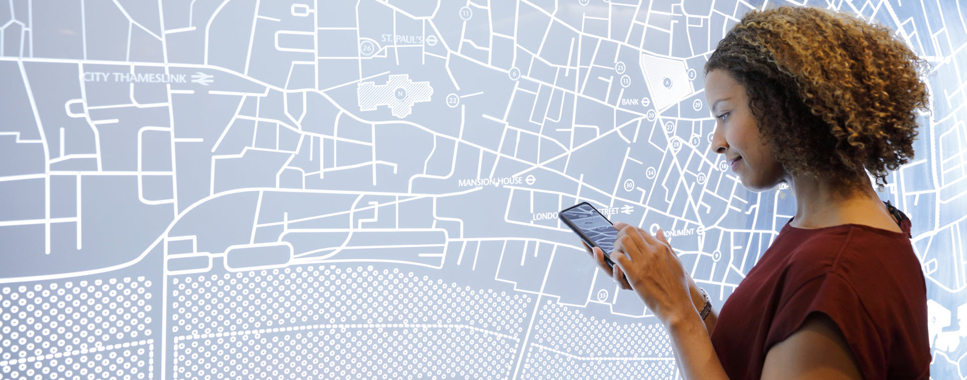 Woman using a smartphone, next to a futuristic map