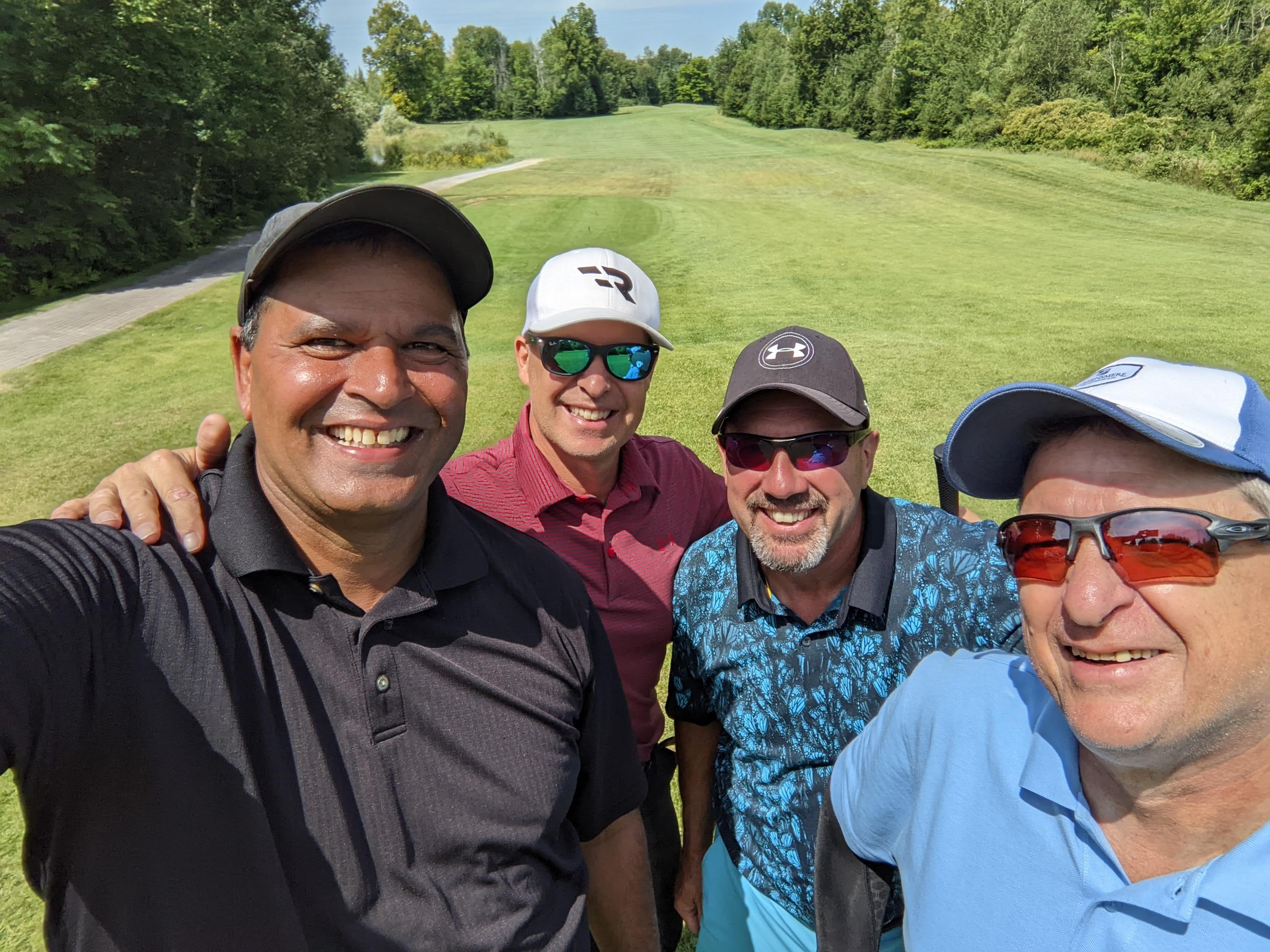 Selfie of four men smiling on golf course