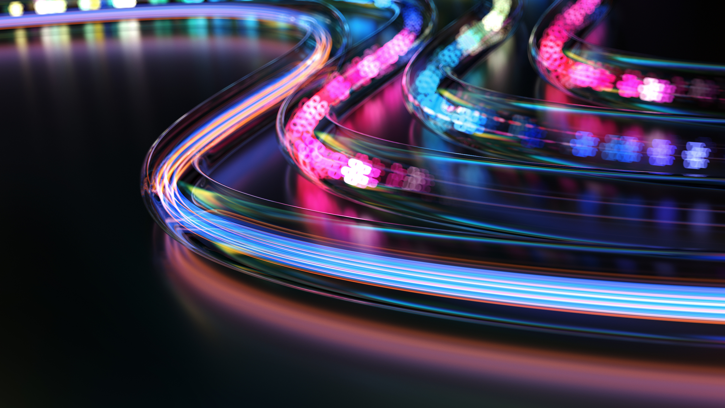 Abstract visualization of fast-moving, multicolored light paths on a dark background, representing high-speed data flow and network connectivity.