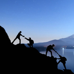 Four people climbing rocks at dusk