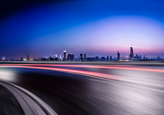 Time lapse image of a road with a city in the background.