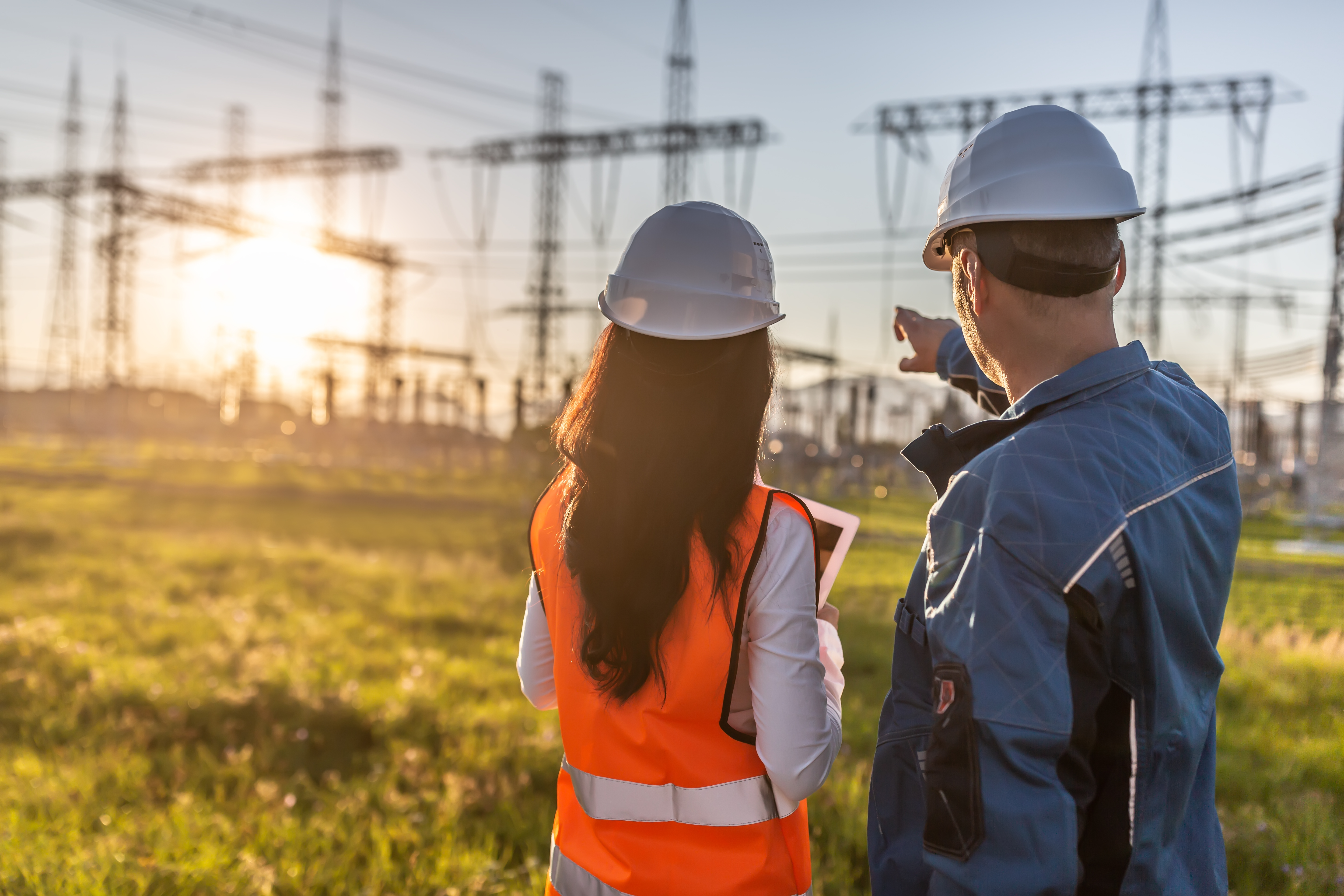 a male and female construction worker looking at a utility plant