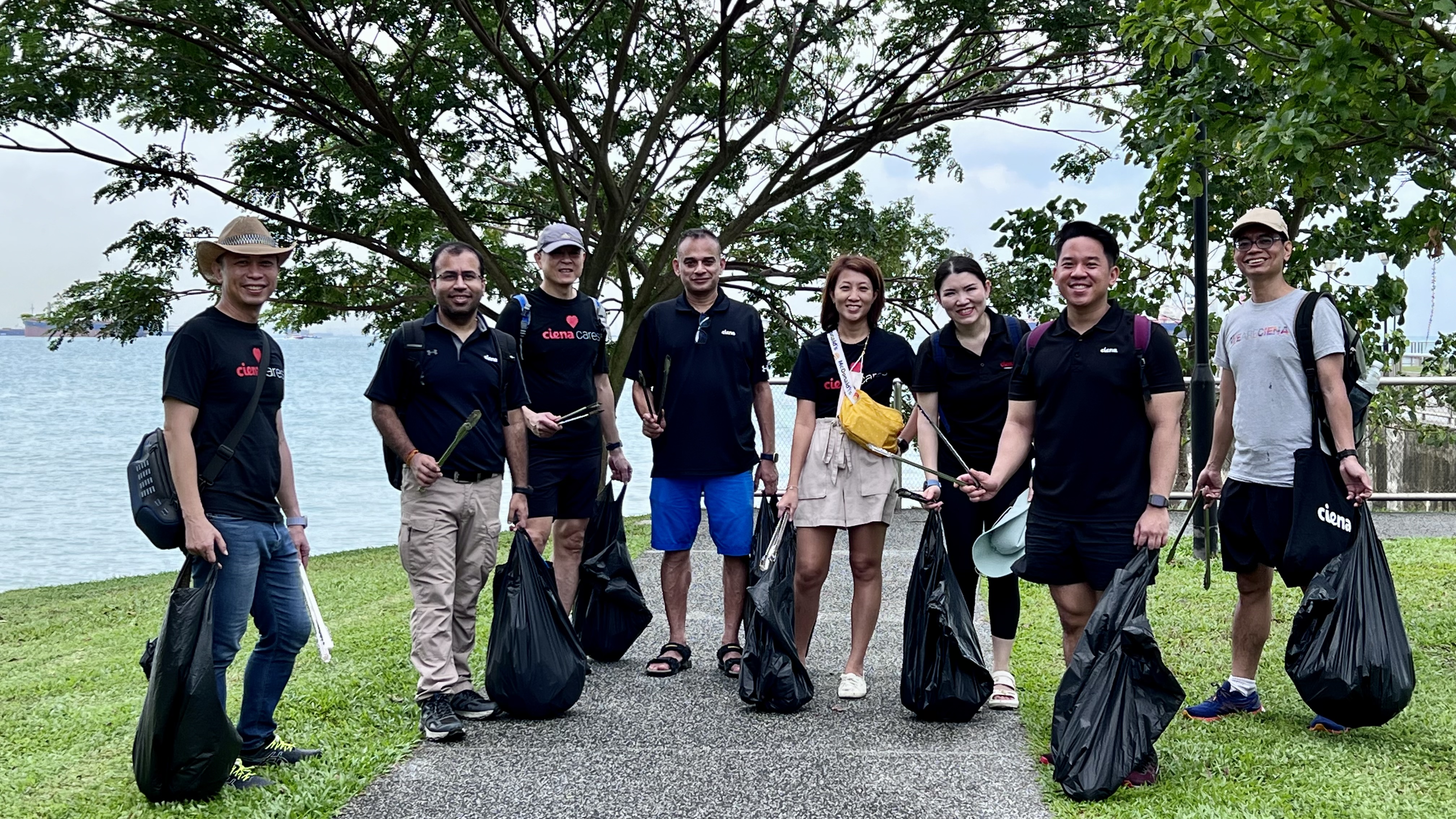 Men and women at a beach with trash bags and tongs to pick up trash