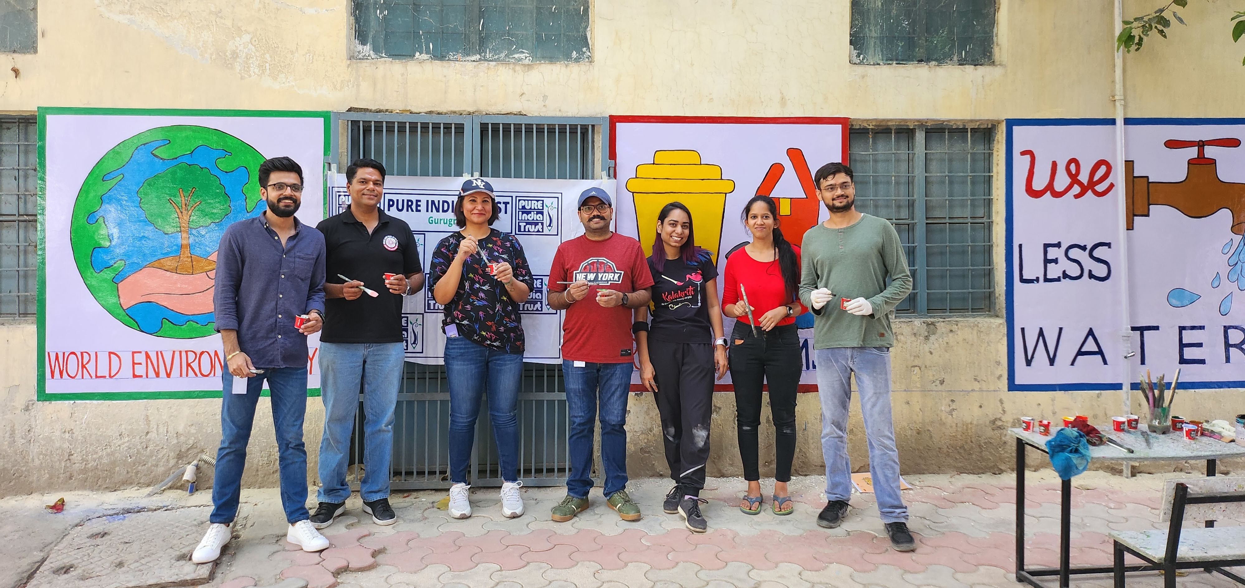 Men and women with paint brushes in front of murals