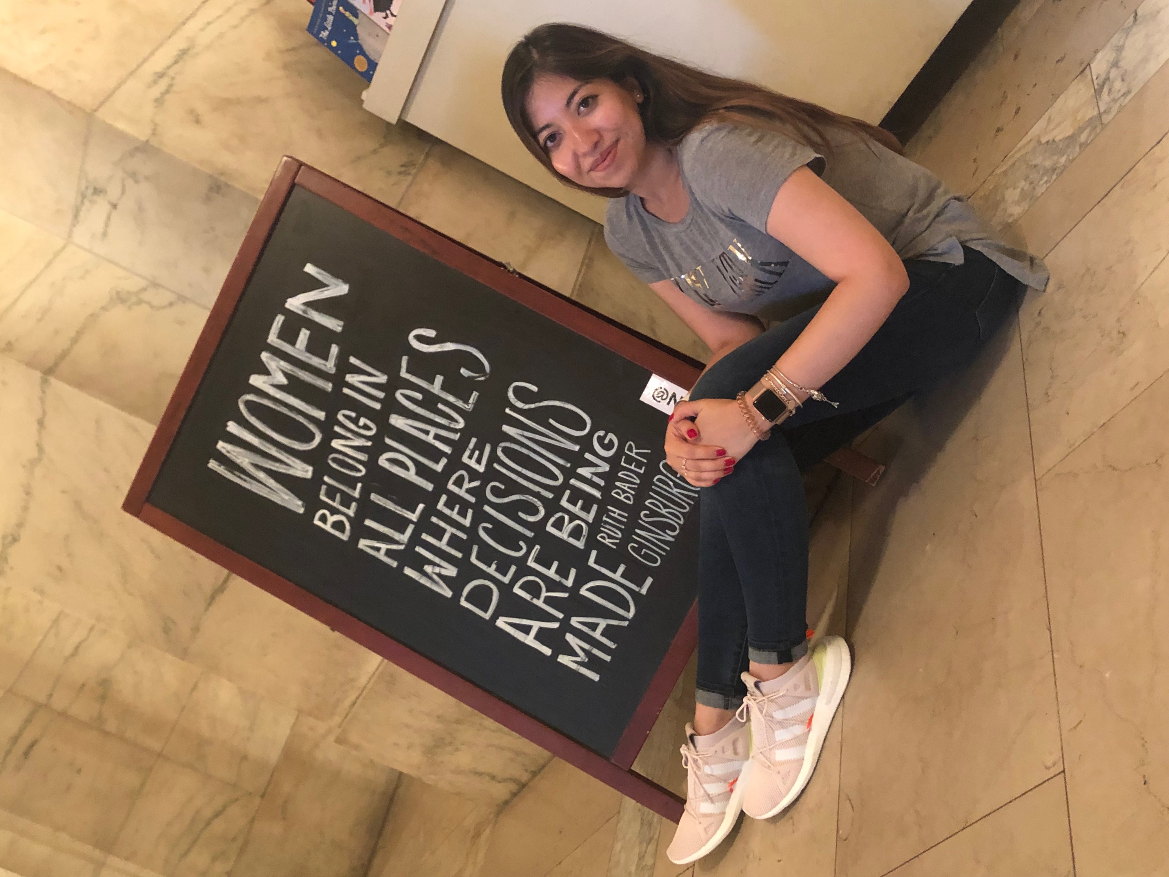 Women sitting on the ground in front of a sign 