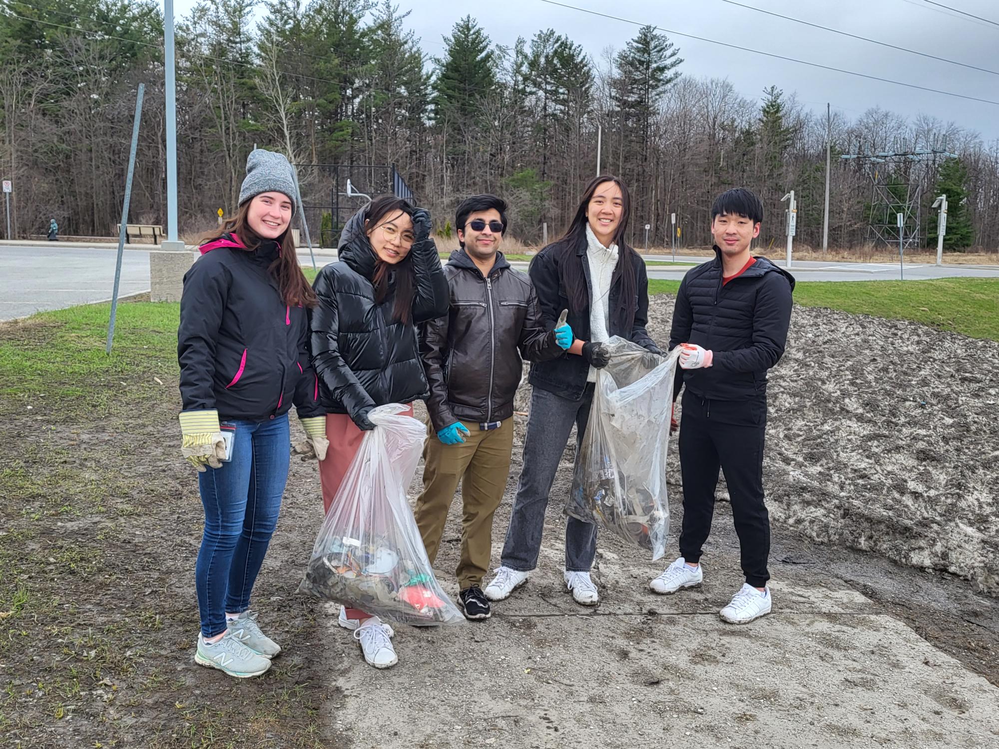 Men and women with a trash bag picking up trash outside 