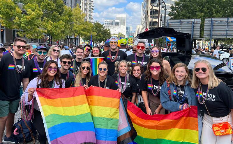 Employees wearing black Pride at Ciena t-shirts and carrying Pride flag