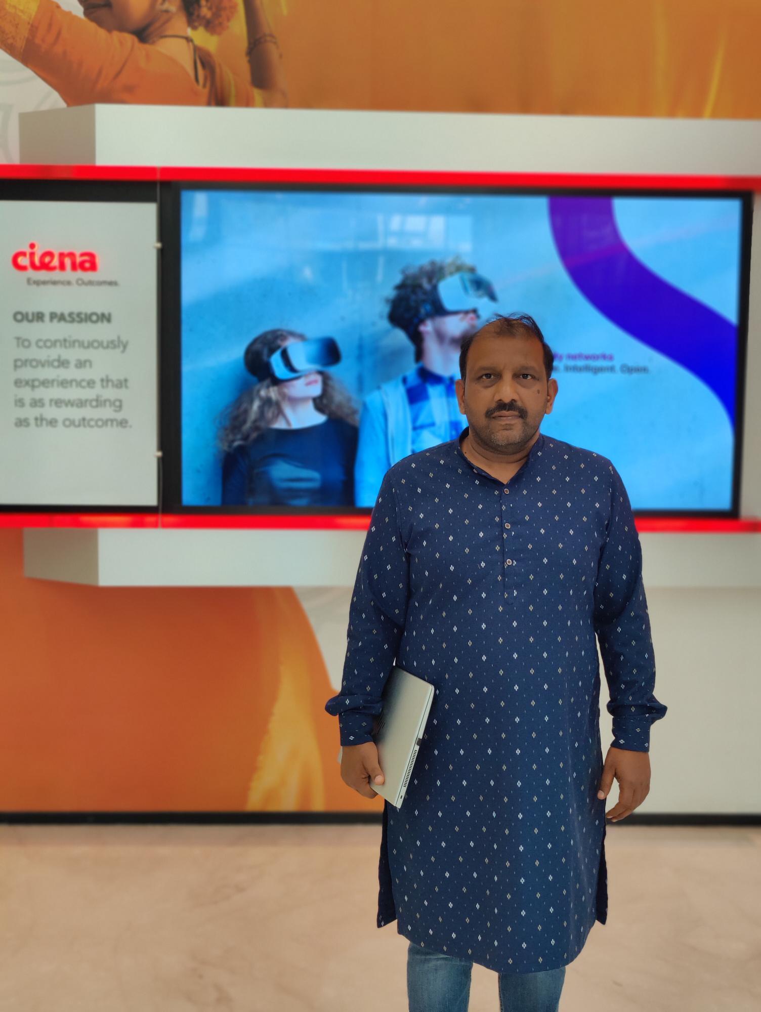 Man standing in front of a Ciena sign 